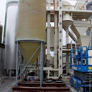 Tussen de beide oude stallen is de nieuwe voerkeuken in aanbouw. Eind november bestond dit uit een bunker waarin de grondstoffen los kunnen worden gestort, zes silo’s voor grondstoffen en een stellage van hamermolens en vijzels om het voer te kunnen malen