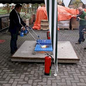 Om  de brandveiligheid te bewijzen, nam Nooyen Pig Flooring de proef op de som en zette de roosterfabrikant het traditionele kunststofrooster (donkerblauw) in vlam en de nieuwe met de speciale coating (lichtblauw).