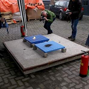 Het donkerblauwe traditionele kunststofrooster vat al snel vlam. De kunststof smelt en wordt voeding voor het vuur. Daarentegen verkoolt het lichtblauwe rooster, maar het rooster blijkt geen voedingsbodem voor vuur te zijn.